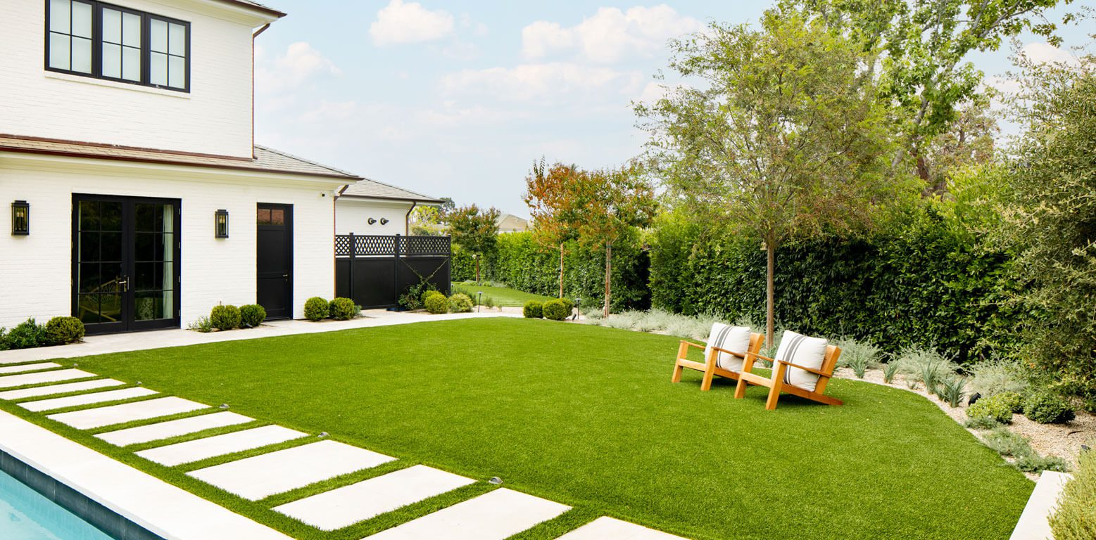 artificial grass installed in backyard with lounging chairs